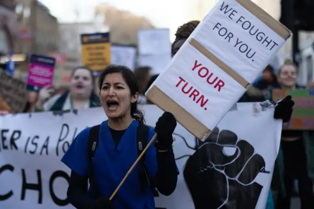 A woman carries a placard which says: "We fought for you. Your turn"