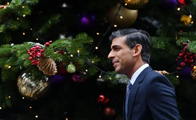 Rishi Sunak walks by a Christmas tree in Downing Street