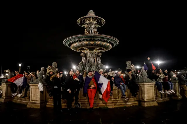 Supporters wait for the arrival of the French national soccer team at the Crillon Hotel