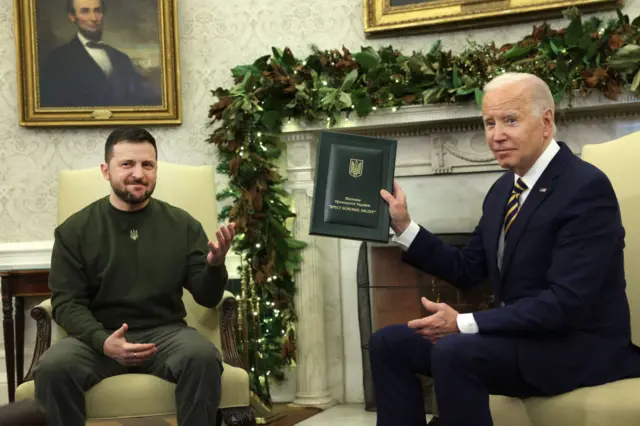 President Biden of American holds up a military award after receiving it from President Zelensky of Ukraine