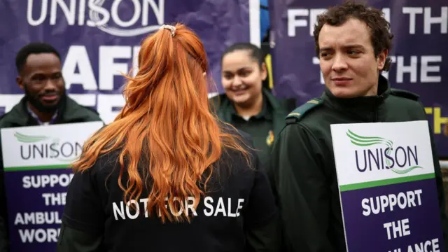 Ambulance workers - one wearing a jumper that says 'not for sale' - strike in London