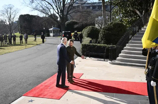 President Biden of America guides President Zelensky of Ukraine along a red carpet