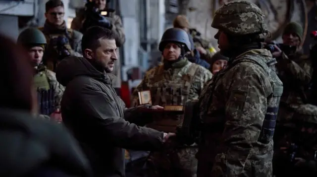 A handout photo made available by the Ukrainian Presidential Press Service shows Ukraine's President Volodymyr Zelensky (L) attending an awarding ceremony of Ukrainian servicemen during his visit to Bakhmut, Donetsk region