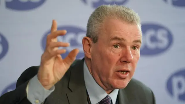 Mark Serwotka, the general secretary of the PCS union, raising his hand as he speaks