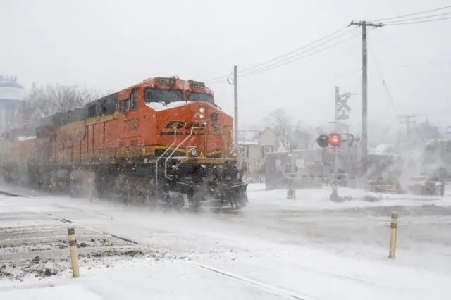 A freight train passes as heavy snowfall begins in a western suburb of Chicago as a winter storm arrives in the Midwest