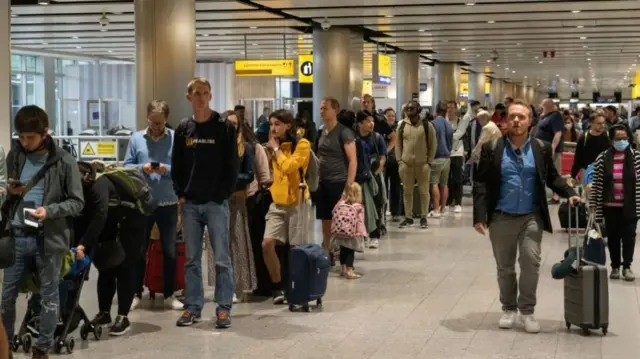 Travellers wait in a long queue to pass through the security check at Heathrow