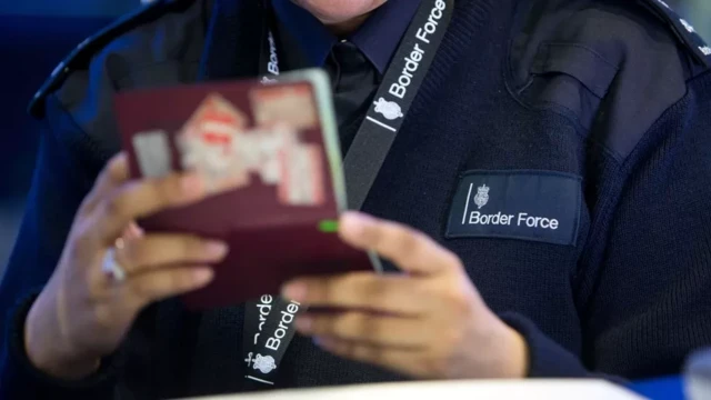 Border Force officer checking passports of arrival passengers in Terminal 2, The Queen Terminal, at Heathrow Airport,