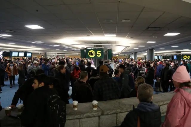 Passengers wait for bags at Vancouver International Airport at just after midnight on Thursday – a number of flights have been cancelled in the US and Canada due to the weather.