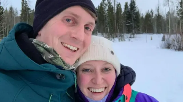 Craig and Katie McBrierty stand in front of a snowy landscape