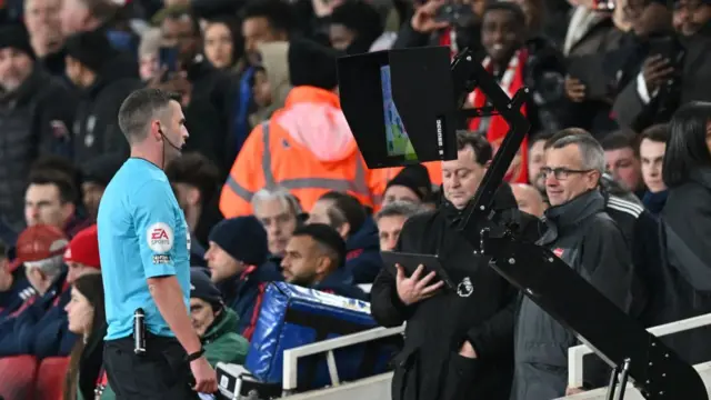 Referee Michael Oliver looks at a screen