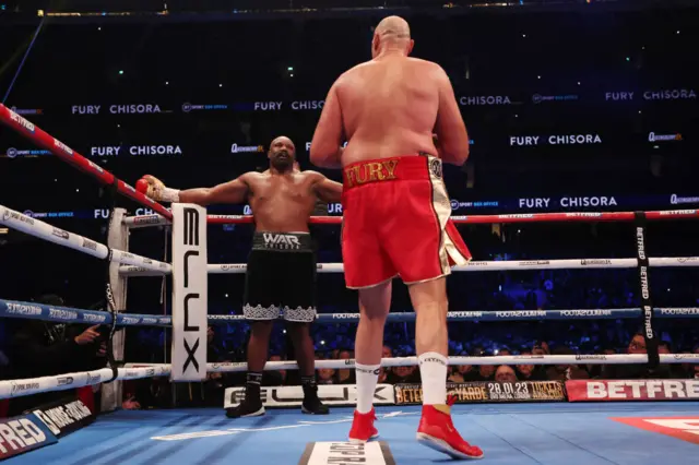 Derek Chisora leans on the ropes in front of Tyson Fury