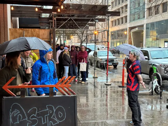 Football fans queue in the rain outside a bar in Washington DC