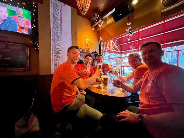 Group of men sat at Dutch bar with beer