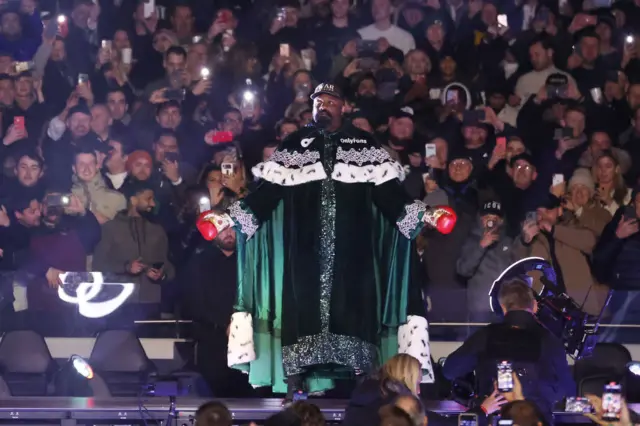 Derek Chisora in a massive green robe with fur