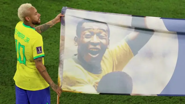 Brazil's Neymar carries a banner of former Brazil player Pele after their World Cup match against South Korea in Qatar