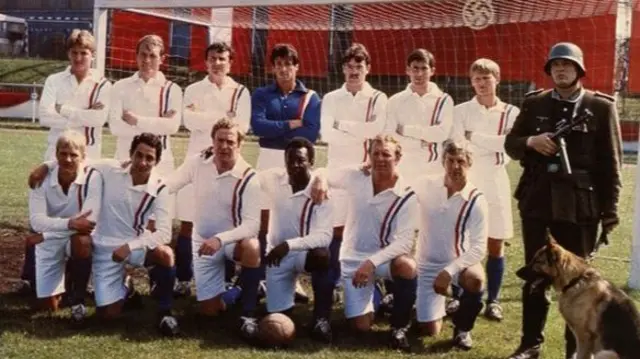 The Escape to Victory team featured actors Sylvester Stallone (goalkeeper), Michael Caine (front, third left) as well as footballers Pele (front, third right), Bobby Moore (front, second right), Ossie Ardiles (front, second left), John Wark (back, third right, Mike Summerbee (back, third left) and Russell Osman (back, first left)