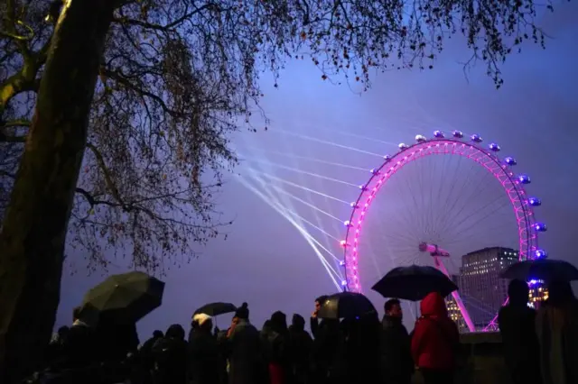 People begin to gather opposite the London Eye in central London ahead of the New Year celebrations