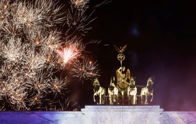 Fireworks explode behind the Brandenburg Gate