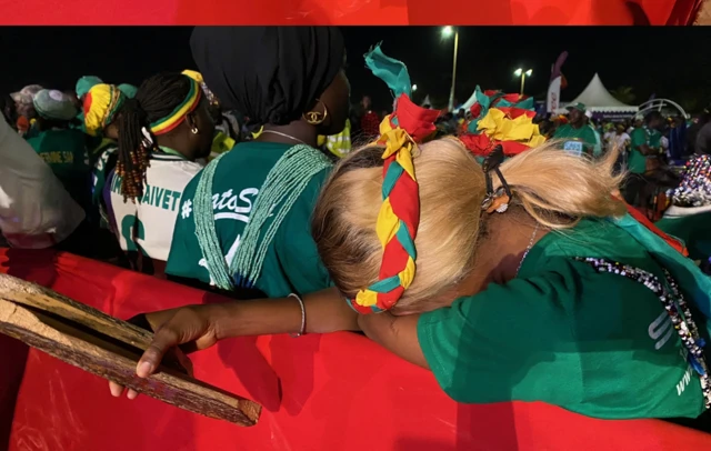 Sad fans in the fan zone in Dakar, one woman in a Sengeal kit has her head in her hands