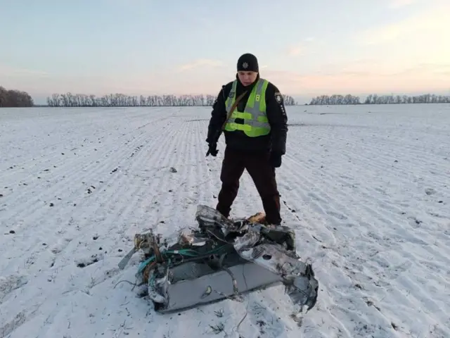 A police officer stands next to part of a Russian missile shot down by Ukrainian air defence systems in Kyiv