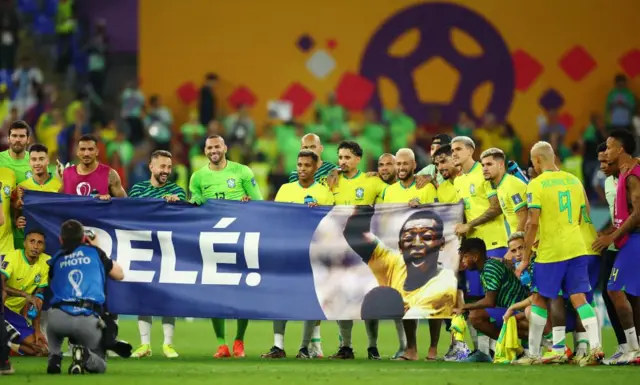 Brazil's football squad holding banner with Pele's name and picture