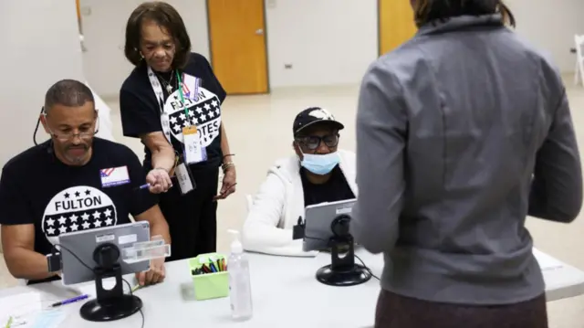 Poll workers help a voter in Fulton County