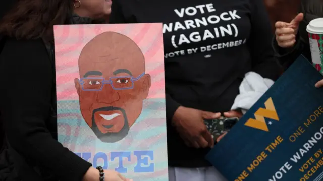 Warnock supporters holding signs