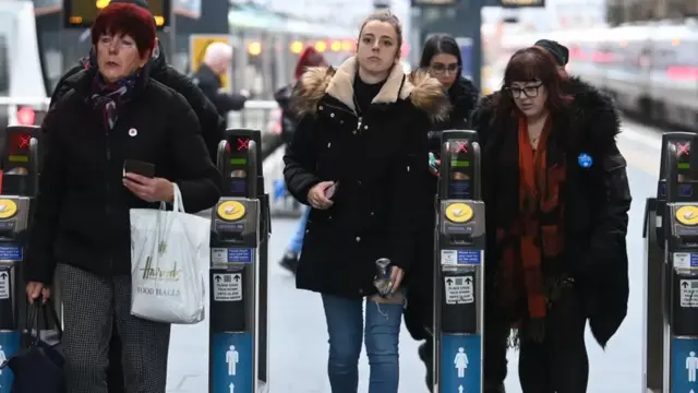 Passengers walking through ticket barriers at a station