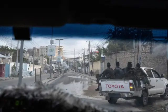 Armed Somali security guards escort an armored vehicle through the city, in dawn light photographed through a window, on streets that are threatened by Al Shabaab explosions in the capital Mogadishu,