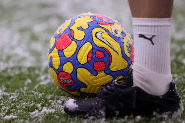 A yellow Premier League ball in the snow