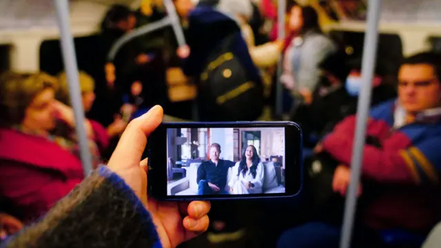 A smartphone showing Harry and Meghan's TV series being watched by a commuter on the London Underground