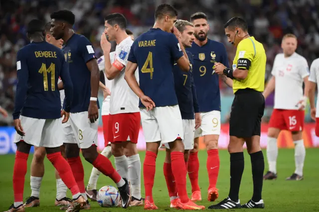 France players argue with referee Jesus Valenzuela after Aurelien Tchouameni is booked against Poland.