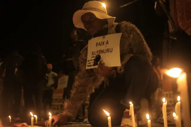 A woman places a candle in Beni on December 7, 2022 during a prayer vigil in remembrance of the victims of the ungoing unrest in the East of the country