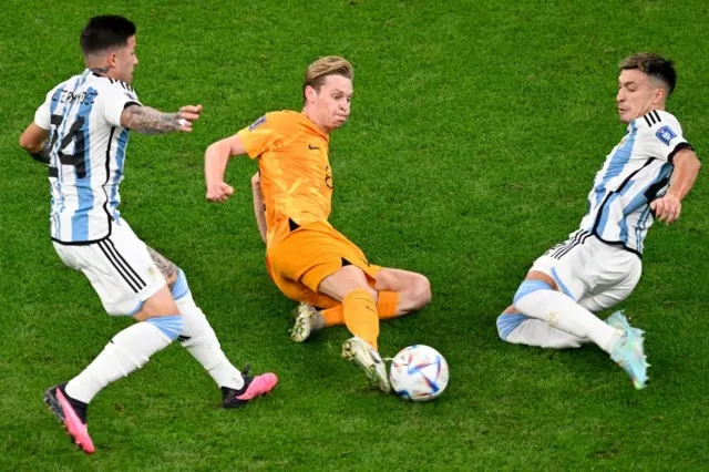 Frenkie De Jong (C) fights for the ball with Argentina's midfielder #24 Enzo Fernandez (L) and Argentina's defender #25 Lisandro Martinez