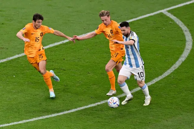 Lionel Messi (R) is challenged by Frenkie De Jong (C) and  #15 Marten de Roon