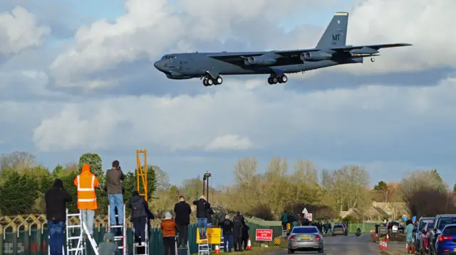 People watch a B-52 bomber land at RAF Fairford