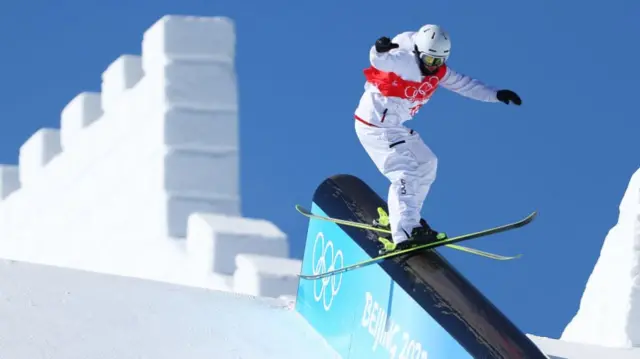 A slopestyle athlete slides down an obstacle