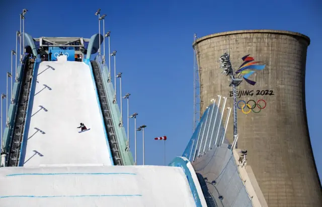 Big air snowboarding next to a power plant