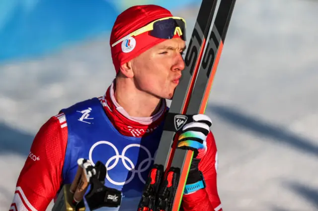 A skiier kisses his skis