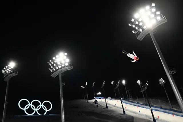 Freestyle skiier in air mid jump with slope in background