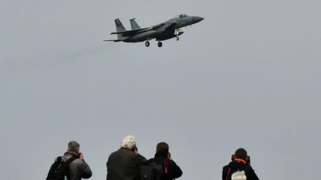 Visitors look on as US F-15 fighter lands during an air force exercise at Starokostyantyniv military airbase in Ukraine in 2018