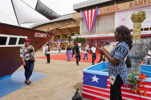 A woman poses in front of a replica of the ship Elizabeth, which was called "The Mayflower of Liberia", during the Liberia bicentennial commemoration in Paynesville, a suburb of Monrovia, Liberia February 14, 2022