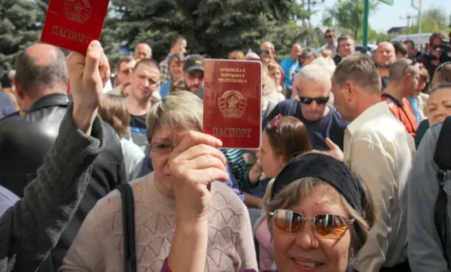 : Local residents hold their passports ahead of the opening of a center where people can submit documents to obtain Russian passports in 2019