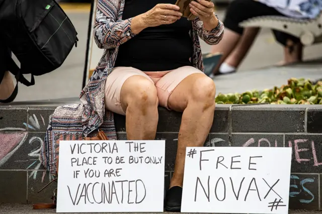 : A Novak Djokovic supporter displays anti-vaccination signage as they gather outside Park Hotel where Djokovic was taken pending his removal from the country after his visa was cancelled by the Australian Border Force on January 06, 2022 in Melbourne, Australia