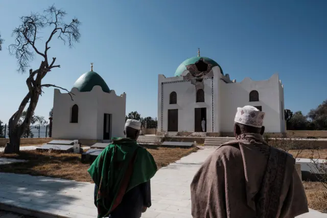 Ethiopian Muslims walk towards a damaged mausoleum at the al-Nejashi Mosque, one of the oldest in Africa and allegedly damaged by Eritrean forces shelling, in Negash, north of Wukro, on March 1, 2021.