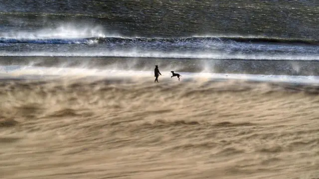 A dog walker on Tynemouth Beach, North Tyneside, before the arrival of Storm Dudley