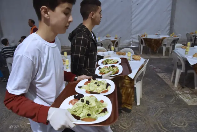 Algerian volunteers from the "Amel Djazair" or "Algeria's Hope" association serve 'iftar' meals to poor families