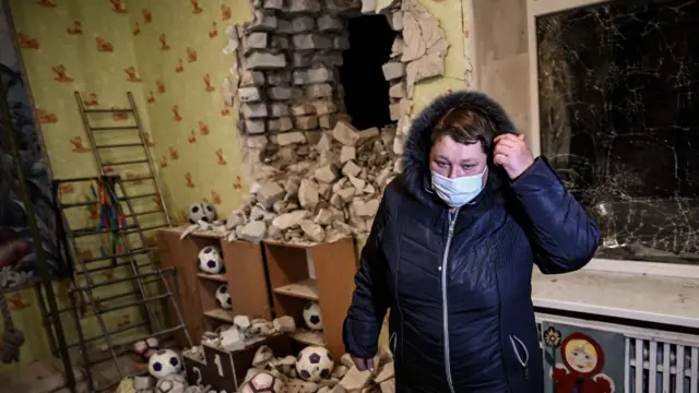 A woman stands among the debris after the shelling of a kindergarten in eastern Ukraine