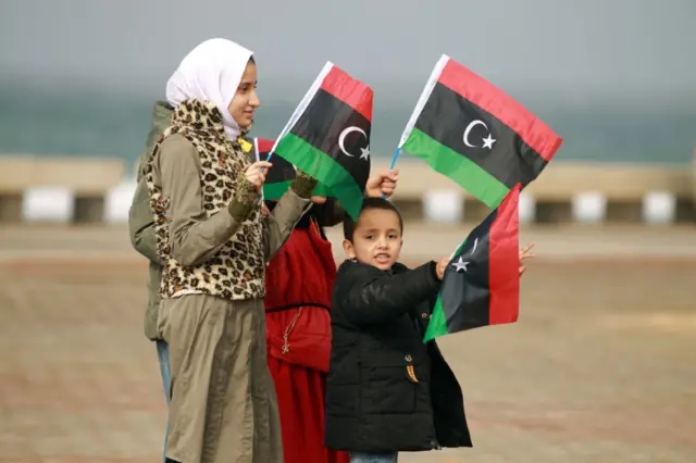 Libyan children hold up national flags during celebrations on February 17, 2022 in Lilbya's eastern city of Benghazi to commemorate the 11th anniversary of the uprising that toppled longtime strongman Muammar Kadhaf