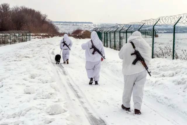 Ukrainian frontier guards walk along the border with Russia